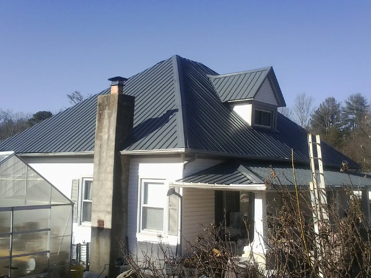 Dark blue standing seam metal roof on a white farmhouse with dormer — Slate & Tile Roof Repair by Roofing Brothers in Princess Anne
