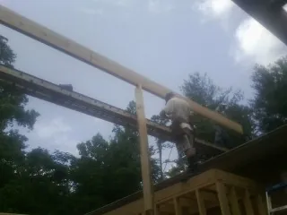 Carpenter setting a ridge beam over a new addition frame — Ice Dam Removal by Roofing Brothers in Princess Anne