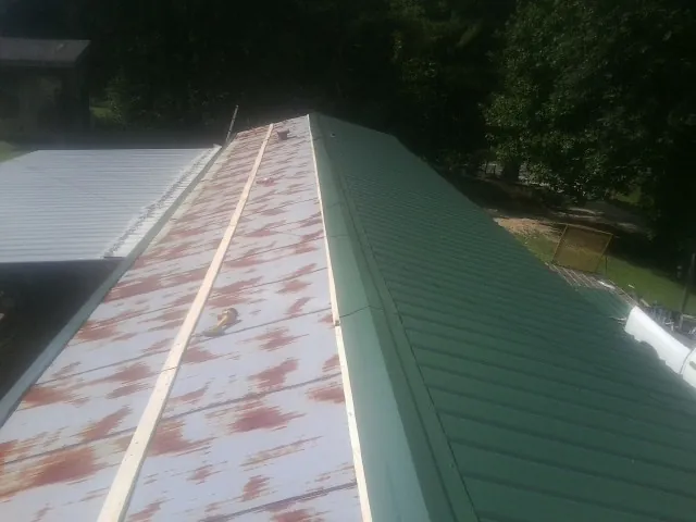 Old rusted panels beside newly installed green metal roofing — Wind Damage Roof Repair by Roofing Brothers in Princess Anne