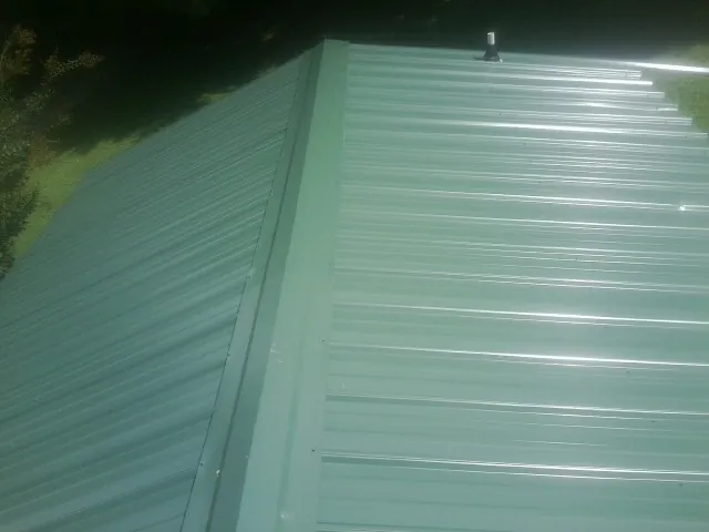 New green metal panels meeting at the ridge of a roof — Flat Roof Repair work by our crew in Princess Anne