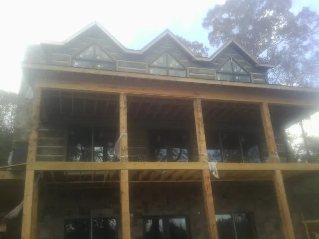 Dormers and porch framing on a large log home under construction — Roof Coating work by our crew in Princess Anne