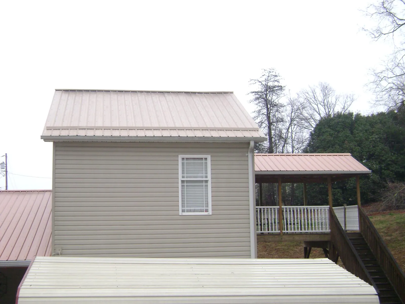 Tan metal roofs on a two story addition and attached porch, from a Roof Replacement job in Princess Anne