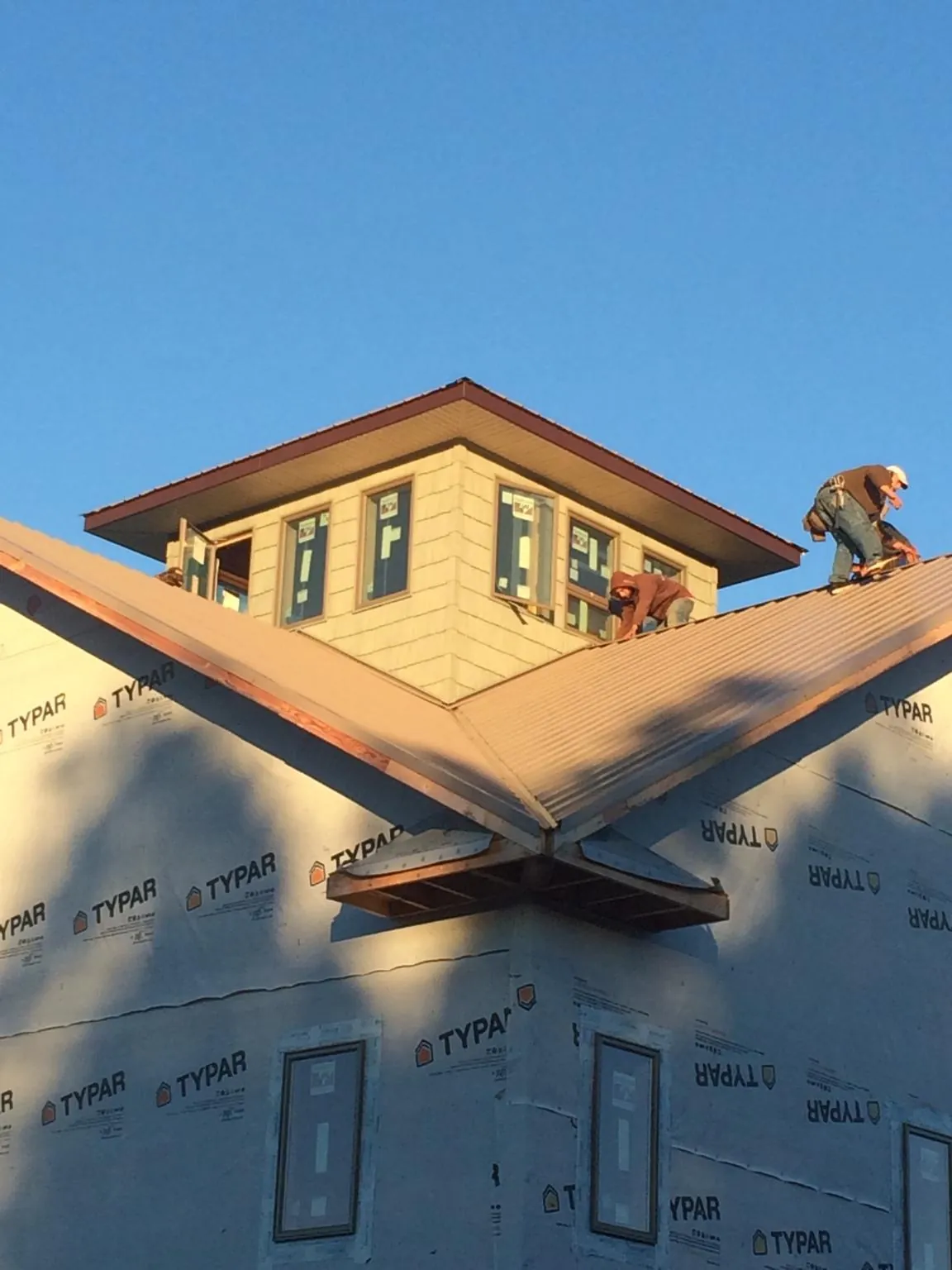 Roofers working around a rooftop cupola on a new metal roof at sunset — Roof Waterproofing in Princess Anne by Roofing Brothers